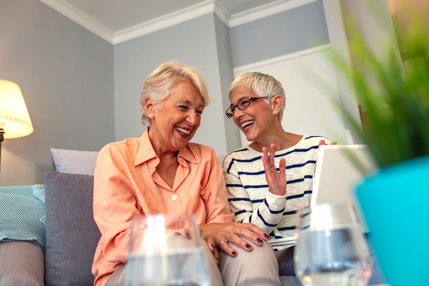 Two senior women using a laptop while seated on a couch