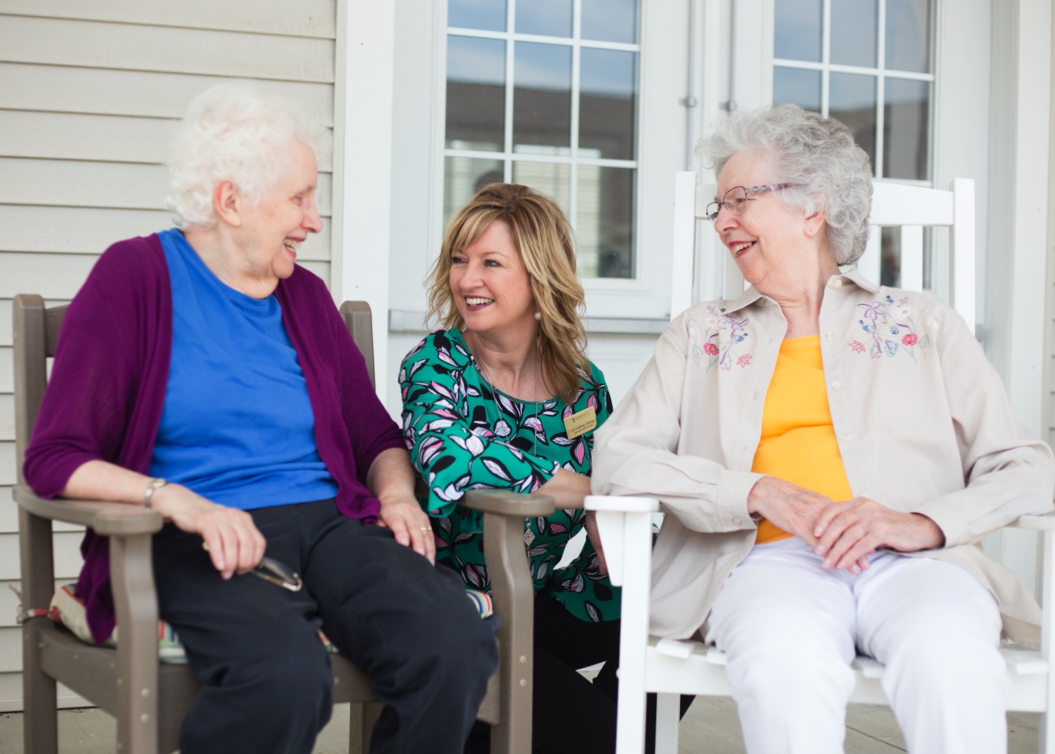 Residents Sitting Outside Laughing With Caregiver